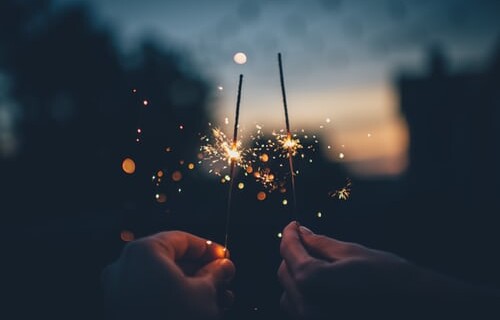 A close up of two sparklers alight in the night