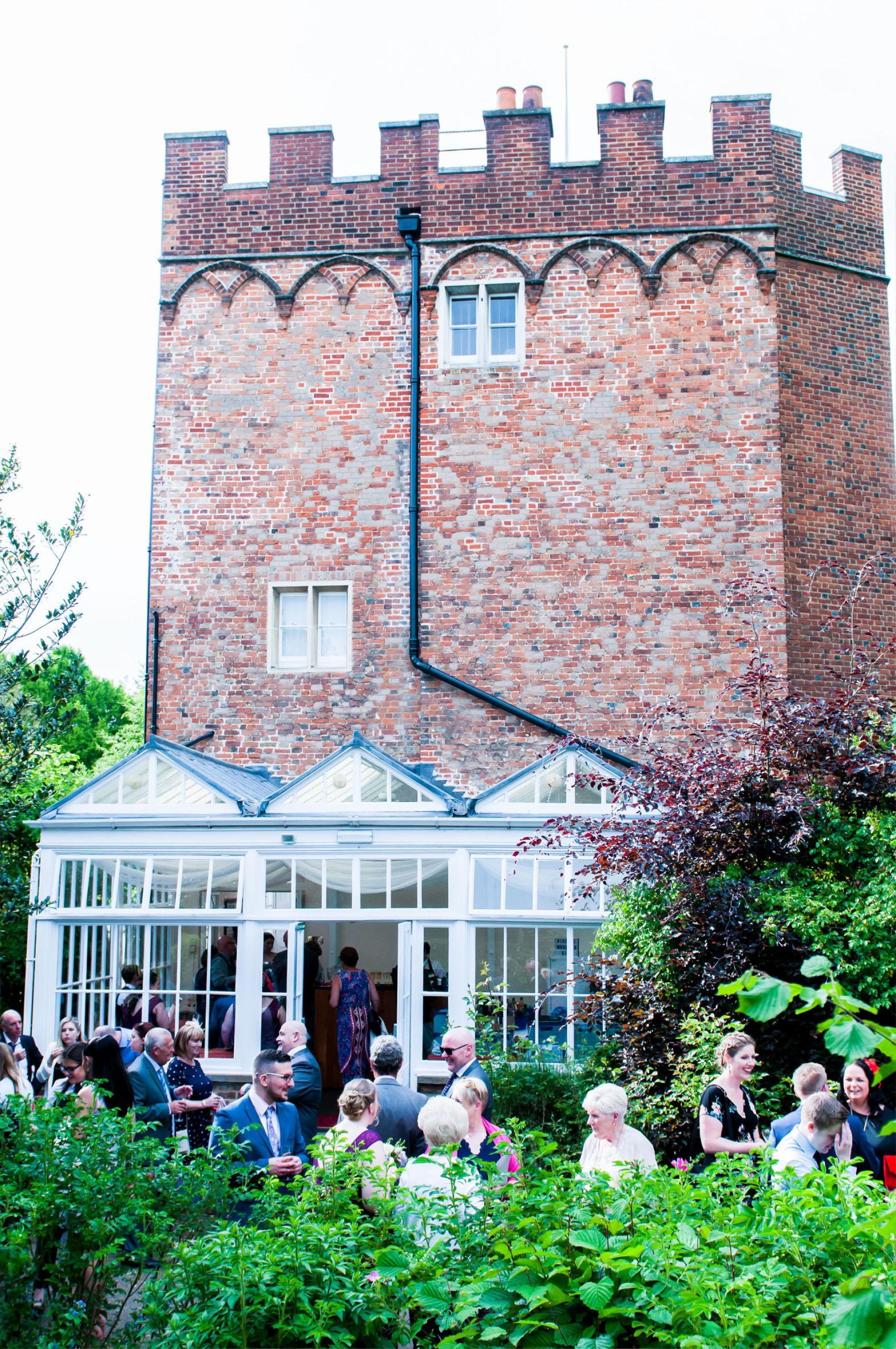 A side view of the castle with the conservatory and guests drinking and laughing together