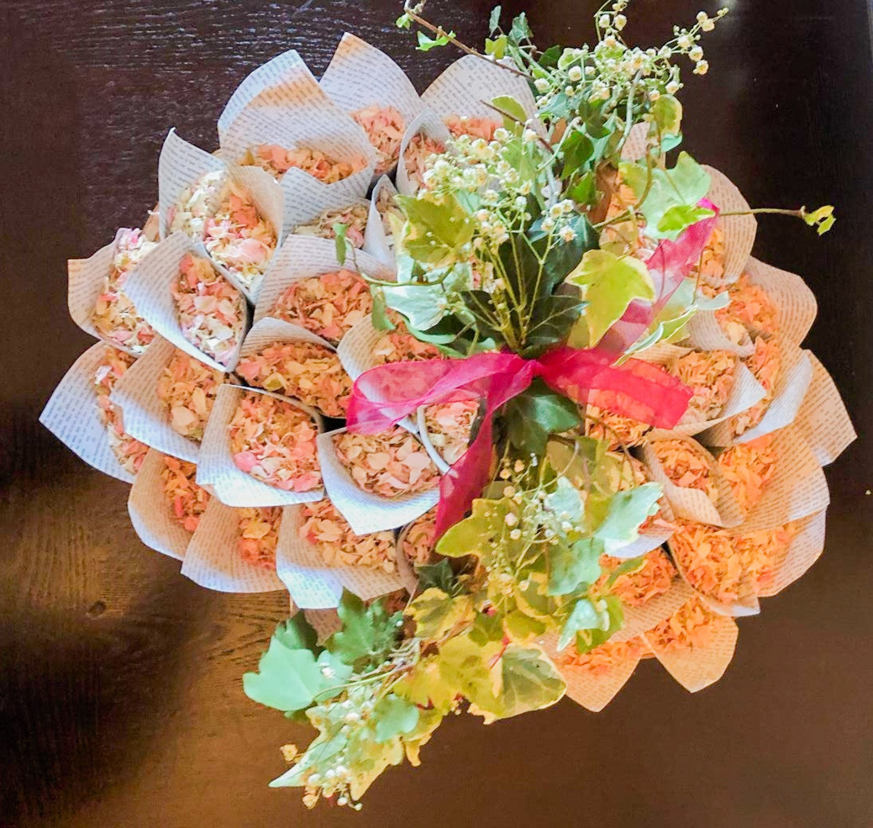 A close up of confetti cones, full of pink confetti and a green floral arrangement in the middle