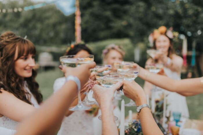 Women holding champagne coupes and toasting together