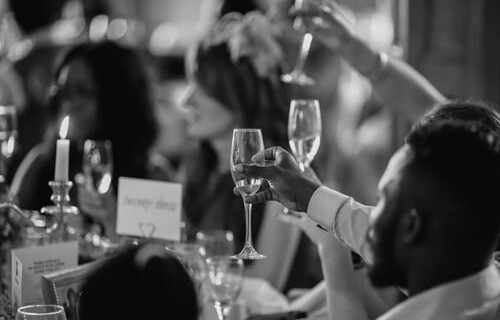 A black and white photo of guest toasting with champagne flutes