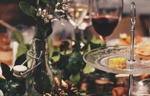 A close up of a table with floral and leaf centrepiece, plates of food and wine glasses