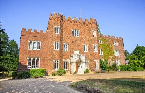 A full shot of Hertford Castle with blue skies above it