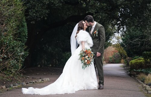 Bride kissing groom in courtyard.