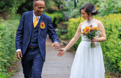 A bride and groom walking through the Castle gardens