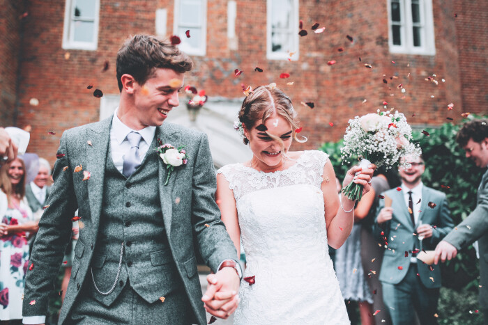 A bride and groom smiling, surrounded by friends and family throwing confetti