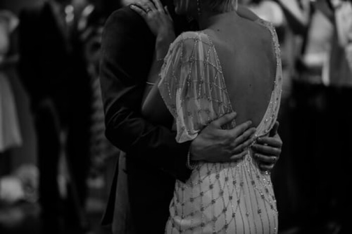 a black and white close up photo of a bride and groom, holding each other around the waist, dancing