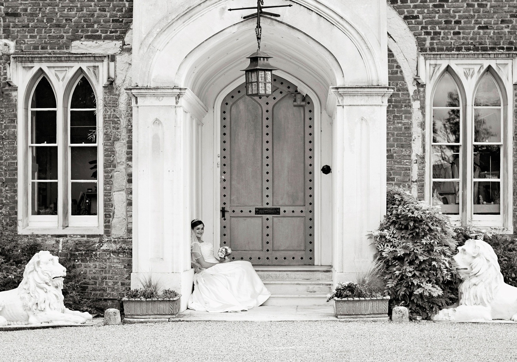A bride sat on the steps out the front of Hertford Castle with the stone white arch above her