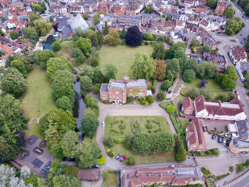 Aerial view of Hertford Castle and Hertford Castle’s greenspace showing the Castle, river, play area, lawns, trees and surrounding town.