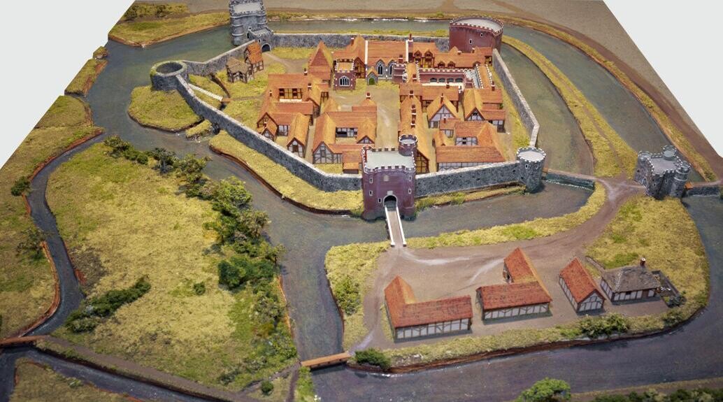 Model representation of Hertford Castle, small orange buildings in the inner courtyard, surrounded by the flint curtain wall. The red brick gatehouse 