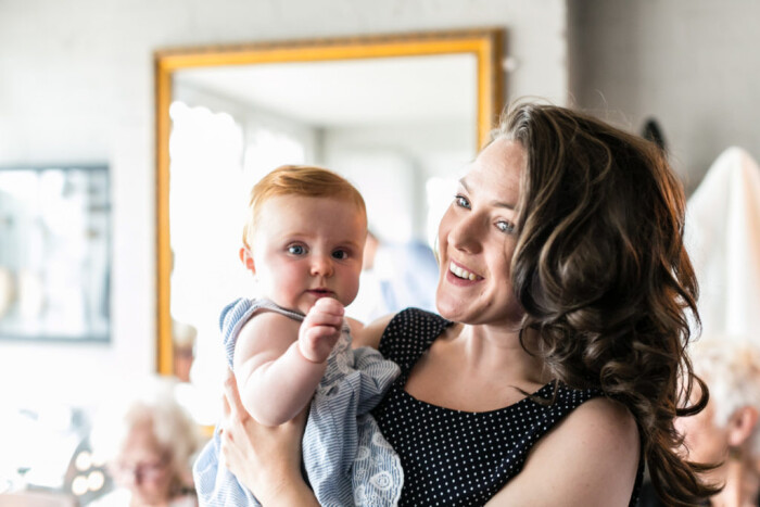 A mother smiling whilst holding her baby 