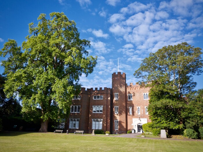 A full shot of Hertford Castle from the main lawn with blue skies above it