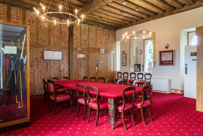 The robing room with a large red velvet covered table, the original brick and timber wall